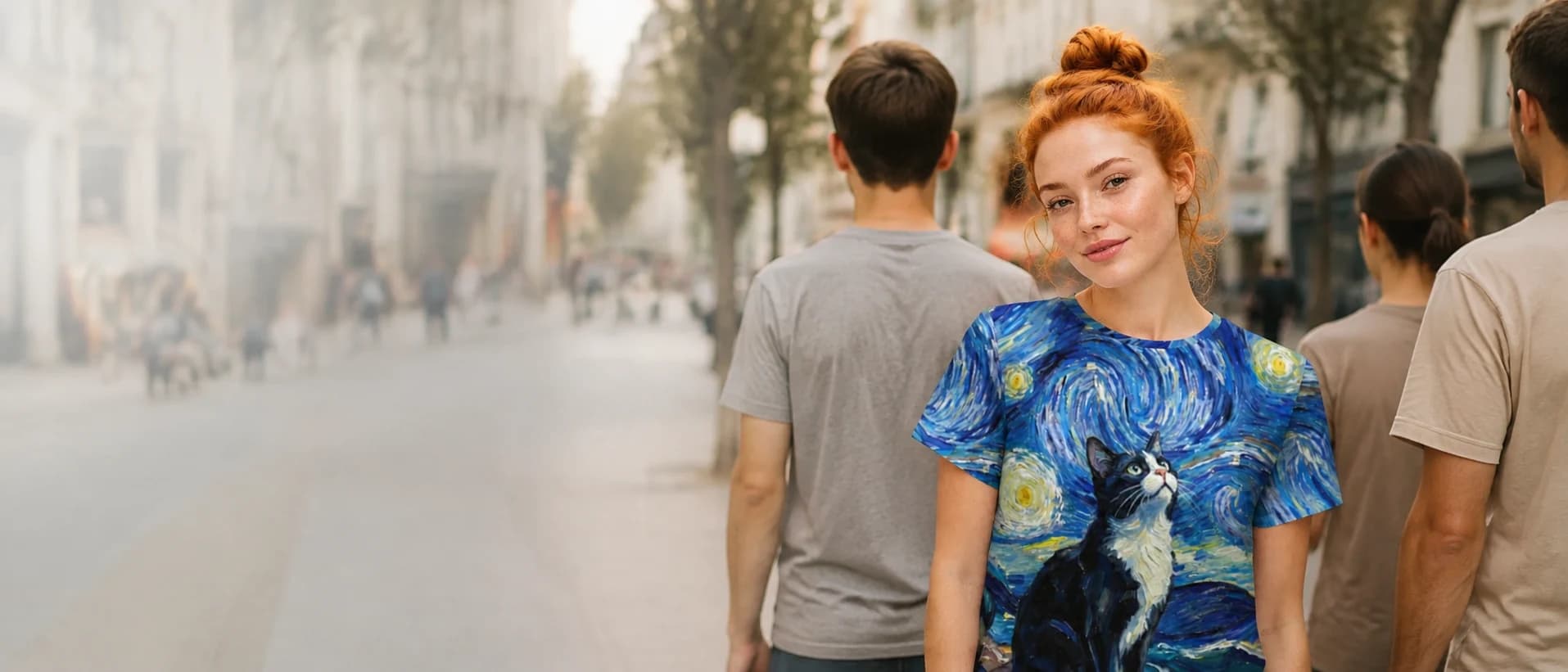 Woman in a blue swirling starry-night t-shirt with a black and white cat, standing on a city street.